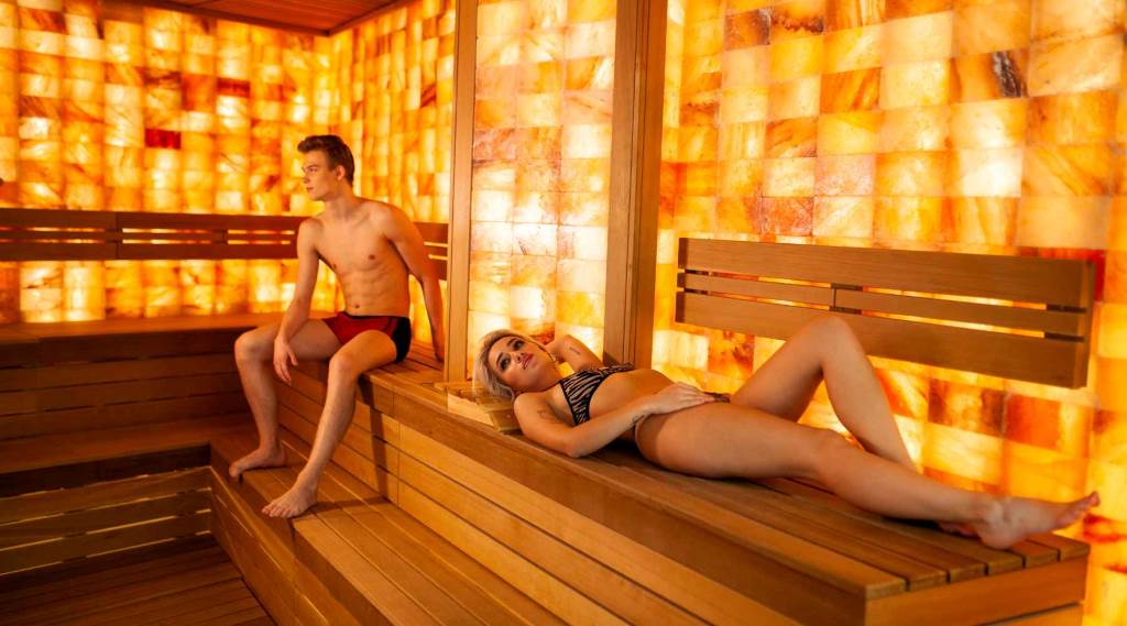 Person pouring water on sauna rocks to create steam.