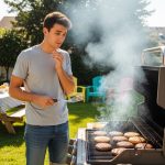 Beginner grilling burgers on a gas grill in a backyard on a sunny day