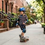 Child wearing safety gear skateboarding in NYC park.