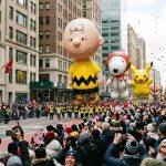 Crowds lining the streets of New York City to watch the Macy's Thanksgiving Day Parade with giant character balloons floating above